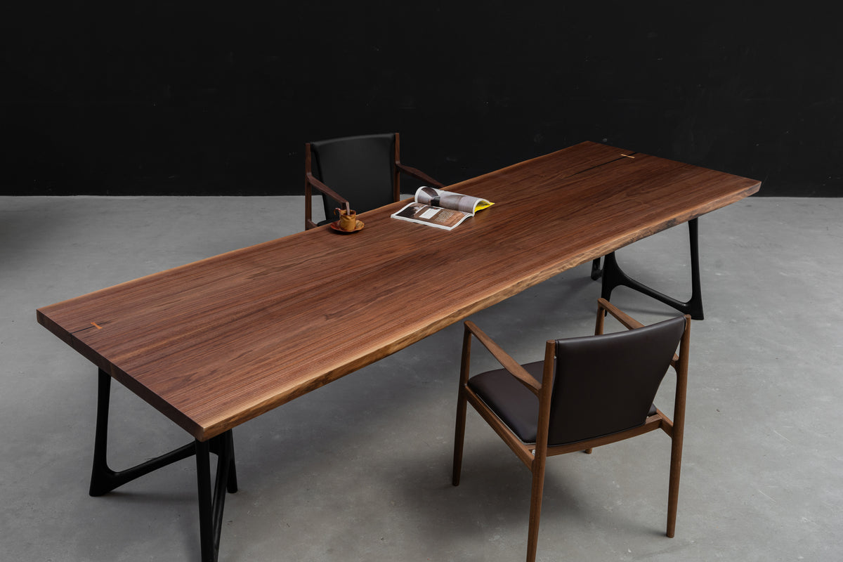 Perspective of the monumental 3.2-meter walnut live edge table styled with high-end leather dining chairs.