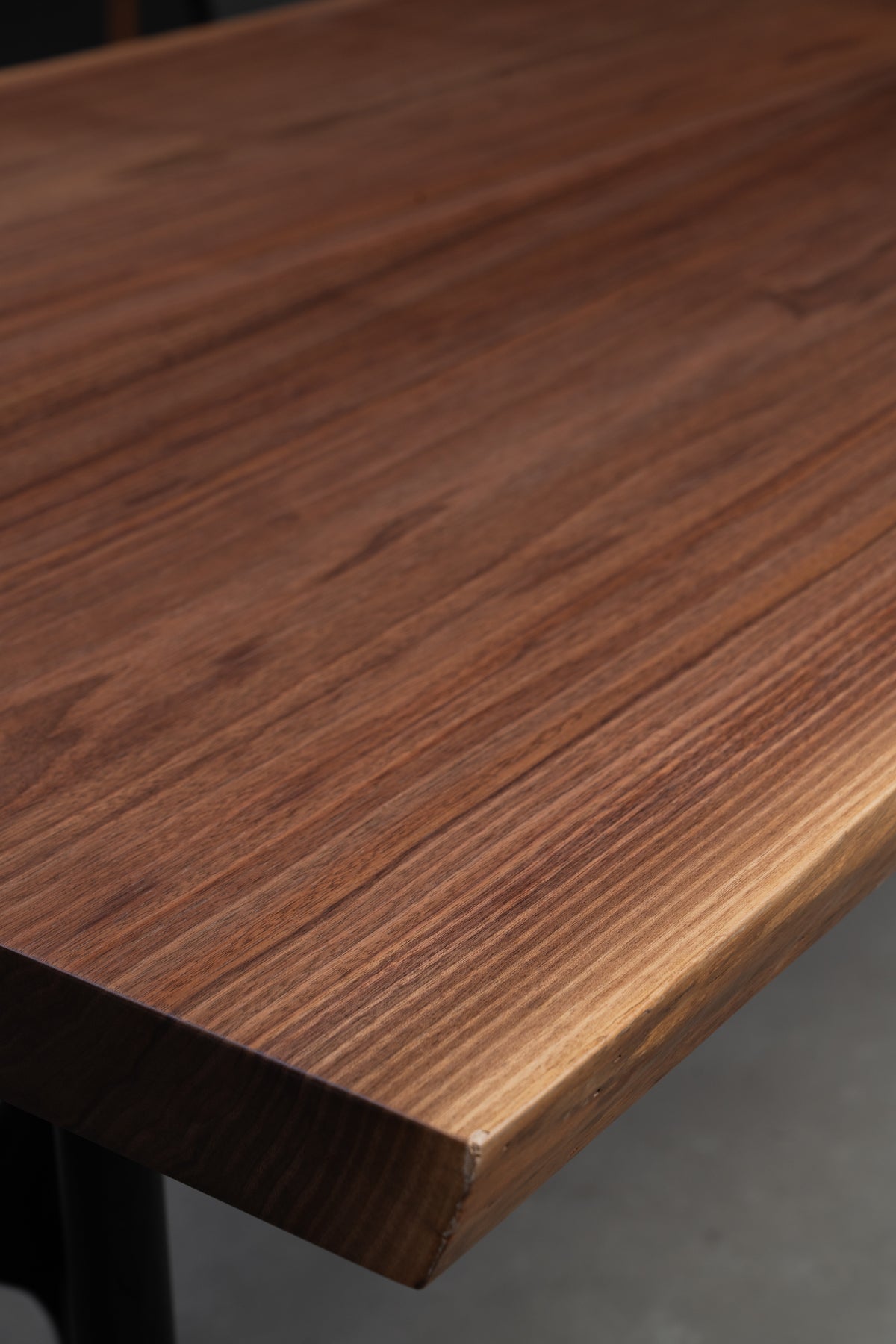 Close-up of the 54mm thick natural live edge and straight-grain corner detail on the Duskwood Bridge walnut slab