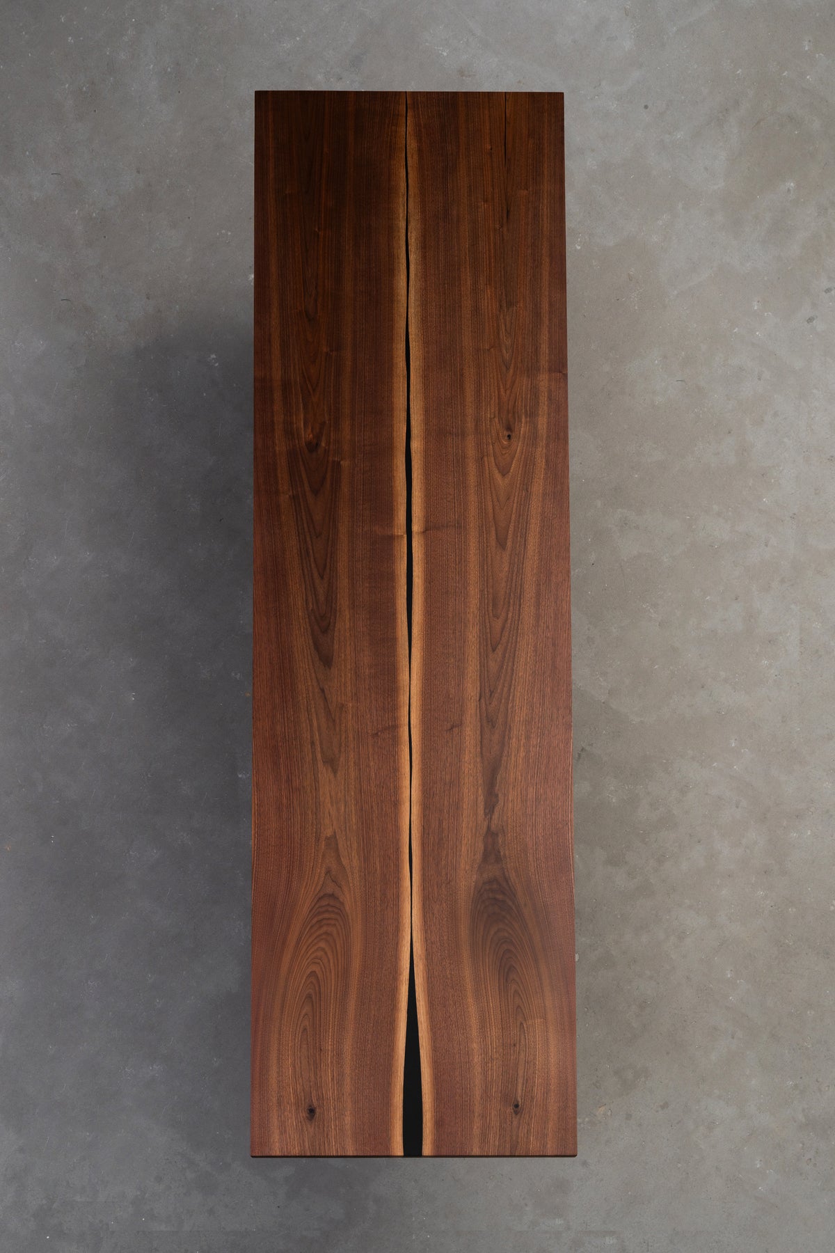 Underside face view of the mirror-image book-matched symmetry and the subtle resin stabilisation centreline. Black walnut table.