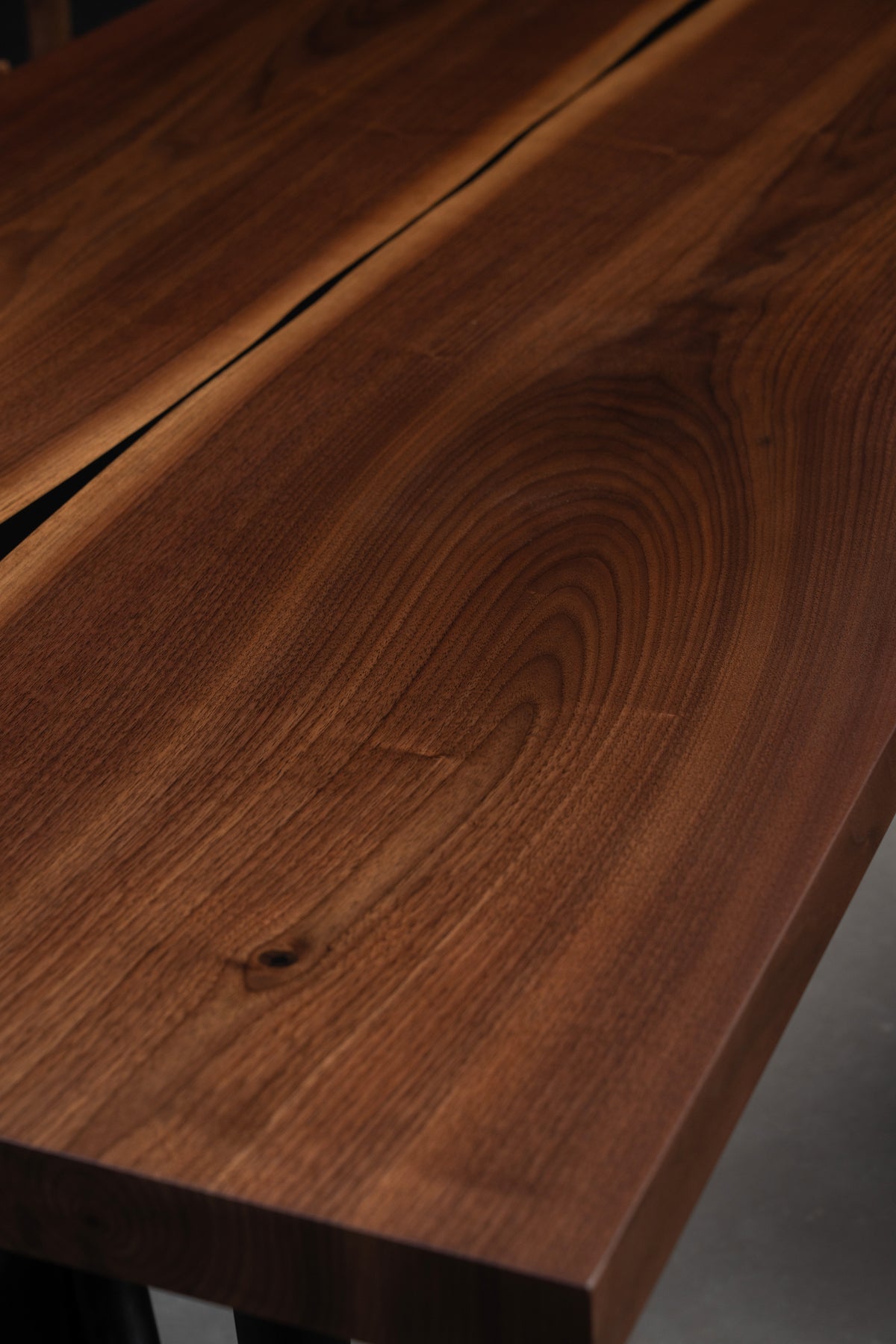 Detailed shot of the precision-cut square edge profile on the Duskwood Vault solid wood slab table with rich black walnut grain.