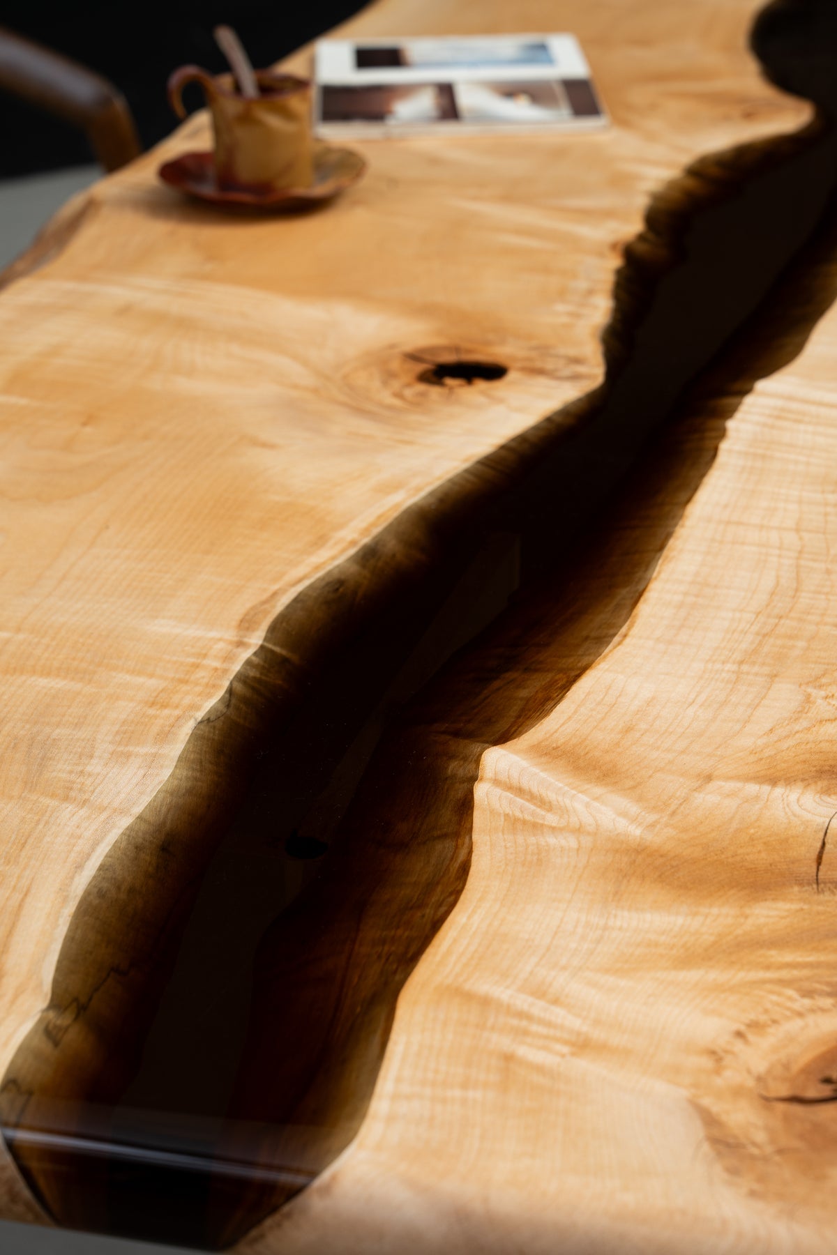 Close-up of translucent earth-tone resin river fused into Japanese Tochi wood slab
