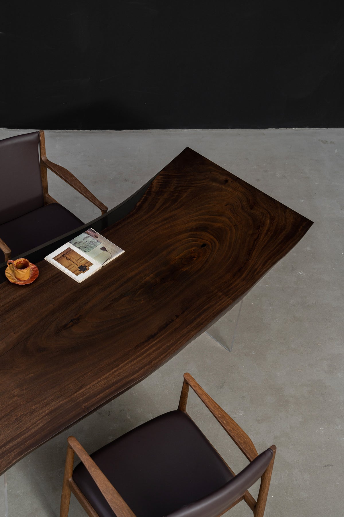 Three-quarter view of Meridian Shores live-edge rainwood table with smooth curves and translucent resin edge