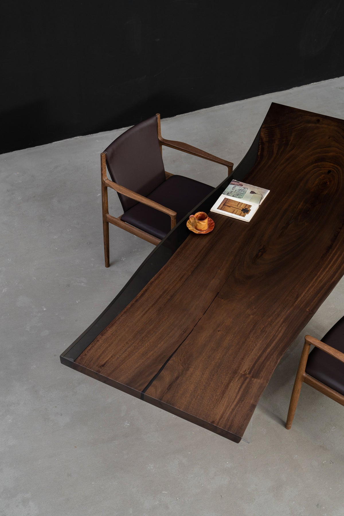 Angled view of rainwood dining table showing natural edge flow and dark translucent resin finish