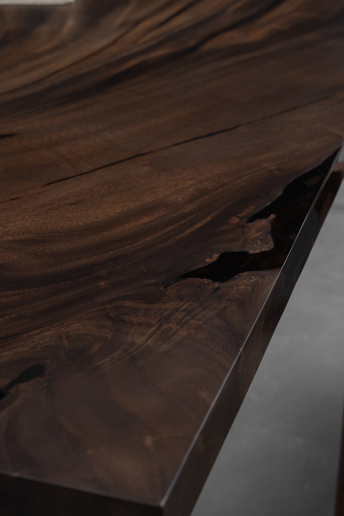 Close-up of the Meridian South Current rainwood dining table showing natural grain patterns and resin accent.