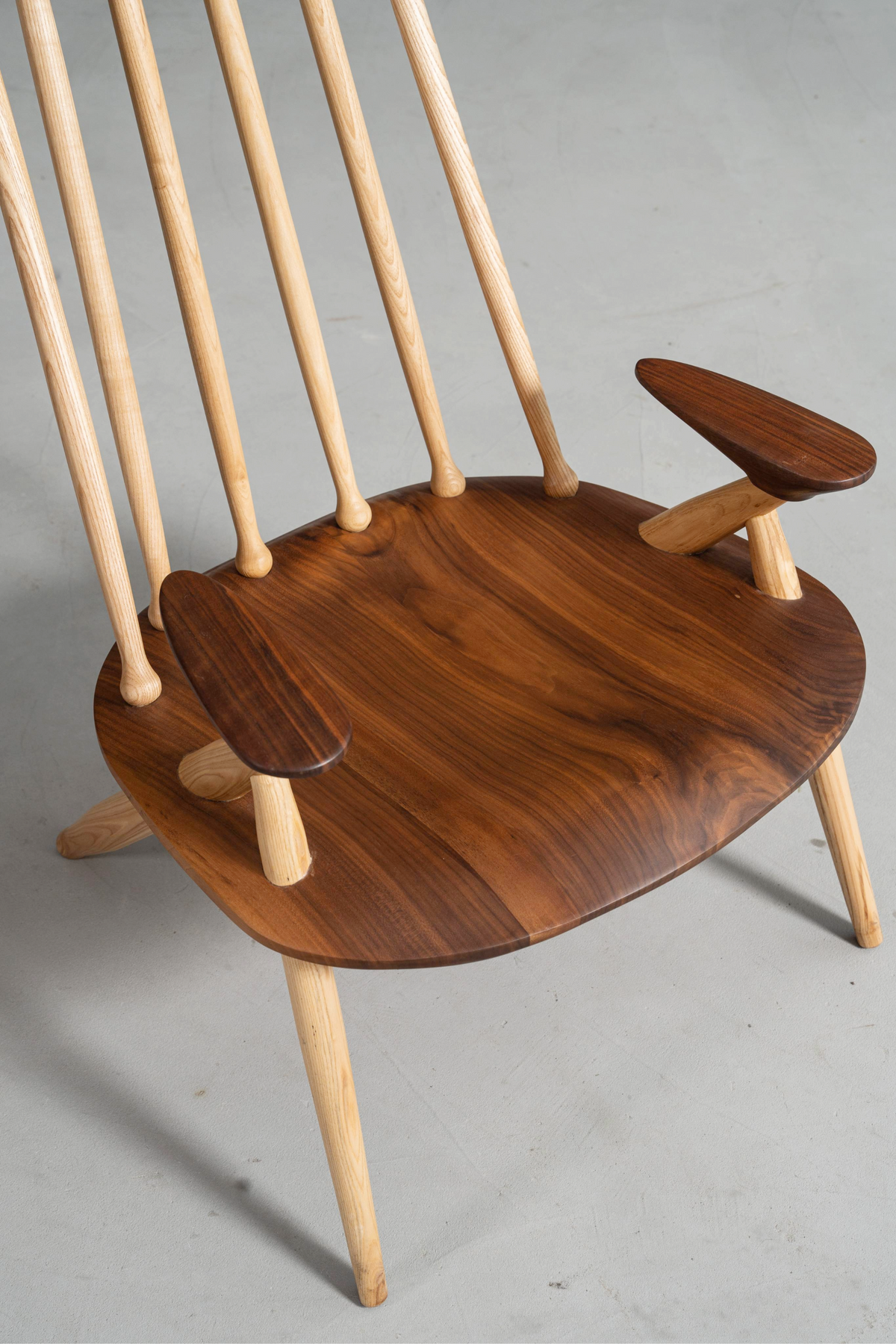 Angled top view of seat and spindles, featuring walnut wood grain and ergonomic form.