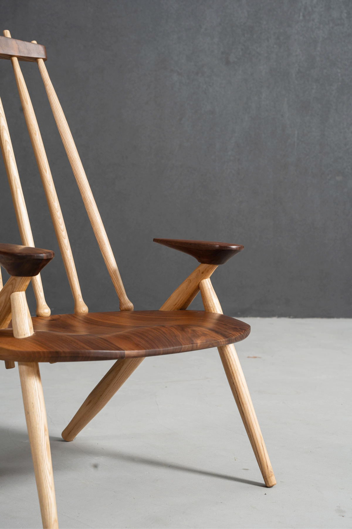 3/4 front perspective of Arcadia Chair showing black walnut and ash wood elements.