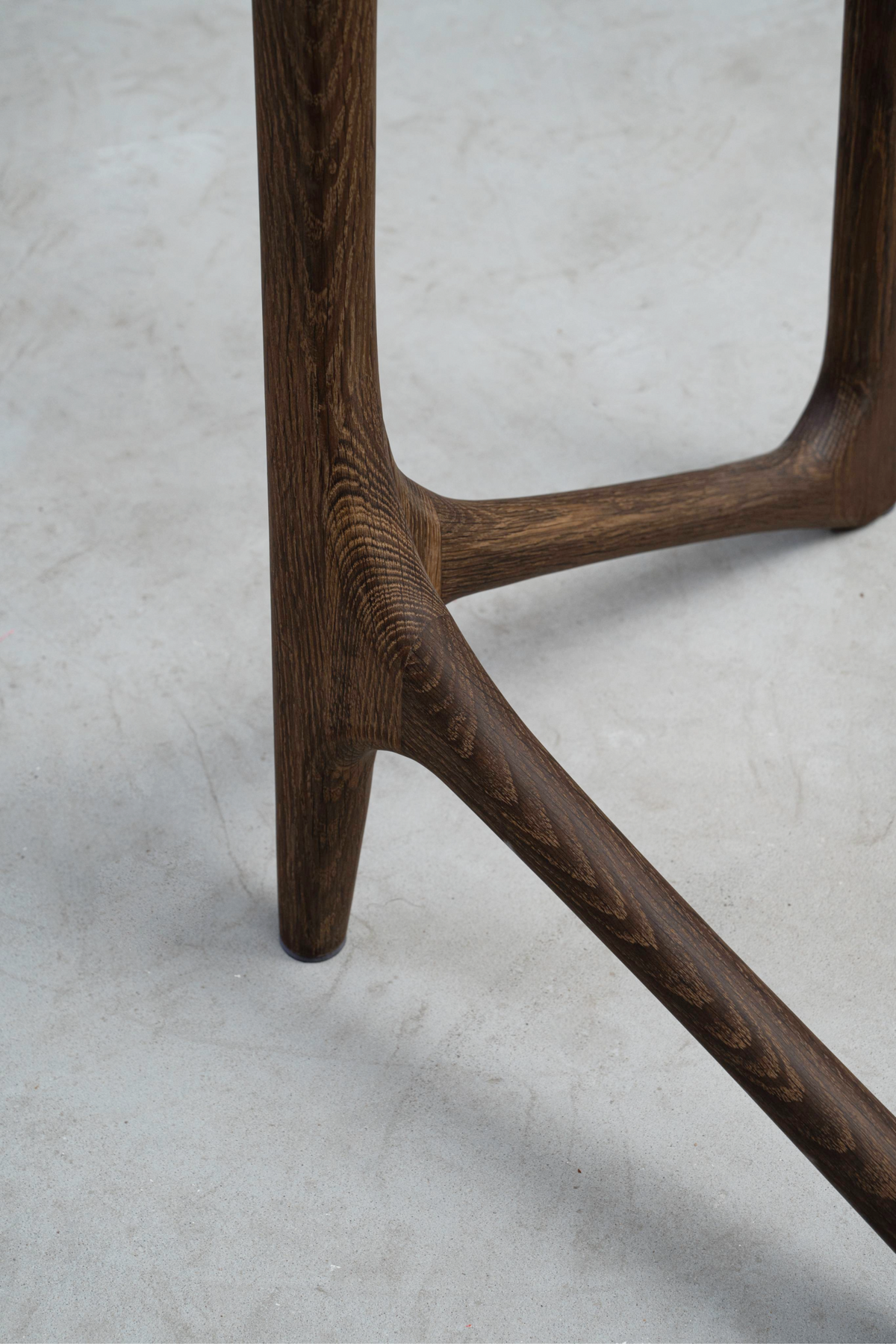 Close-up where the Butterfly Effect base meets the floor, showcasing smoked oak's clean edge and support.