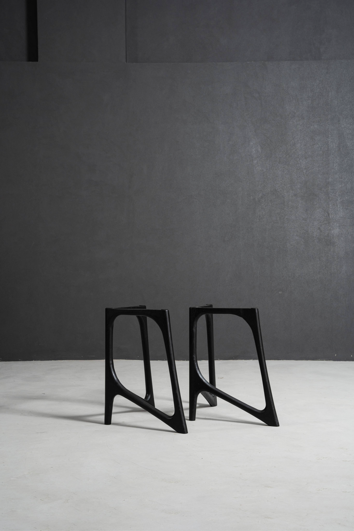 Woodslabs' Butterfly Effect T-Stands in black stained oak on a minimal concrete background.