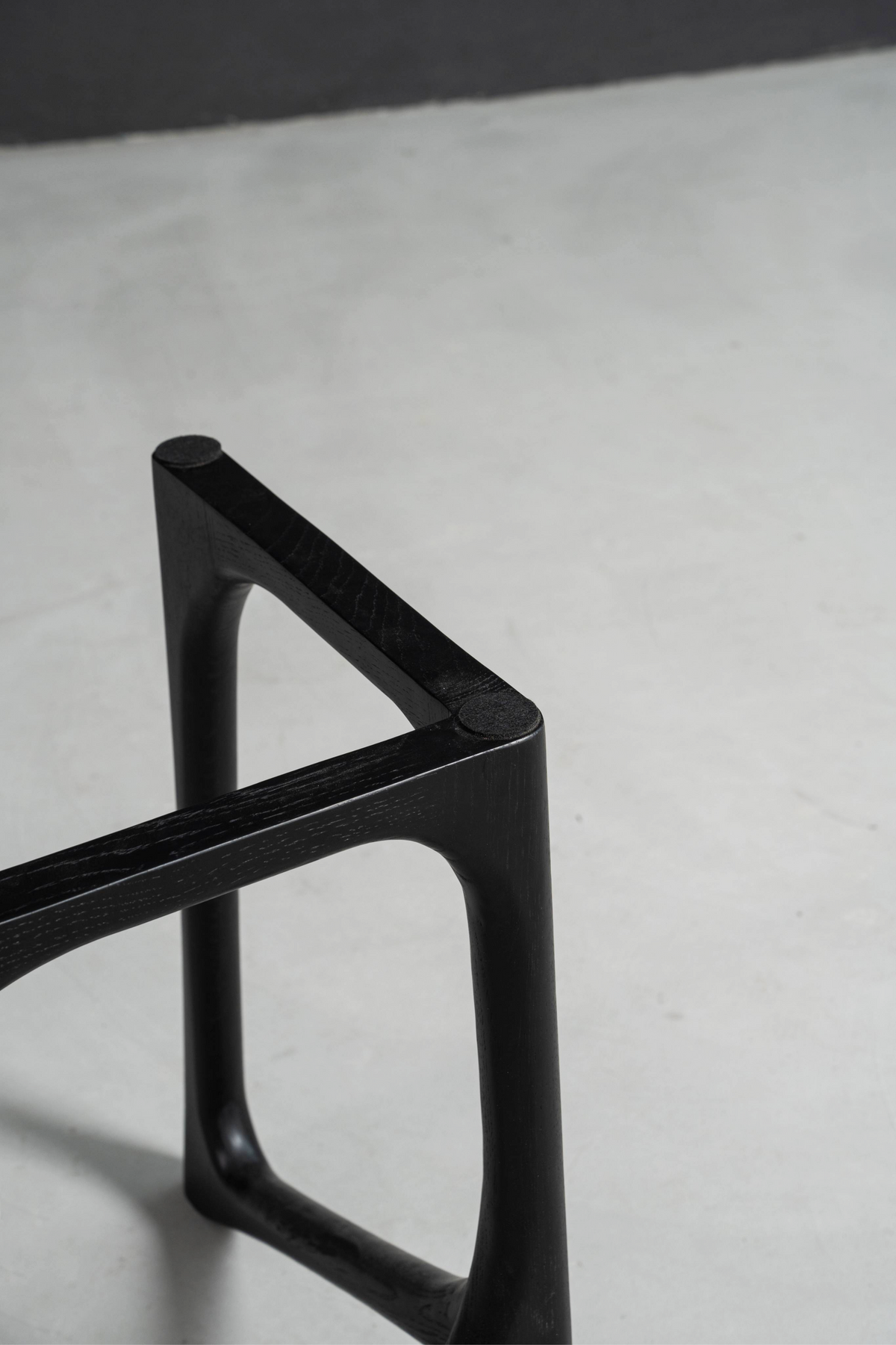 Close-up detail of Woodslabs' black stained oak Butterfly Effect T-stand, showcasing the precision joinery.