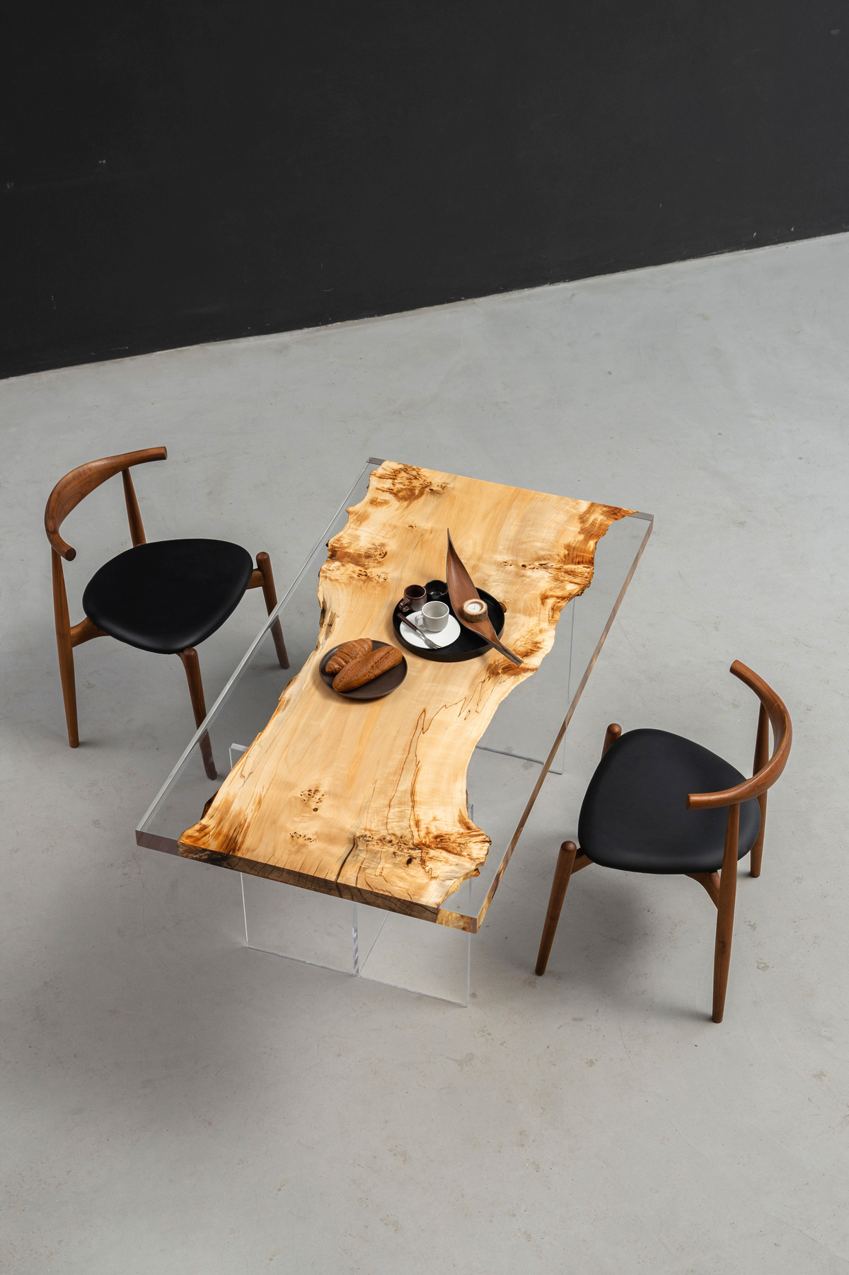 Top-down angled view of Clarity Prism dining setup with chairs and minimalist base in context.