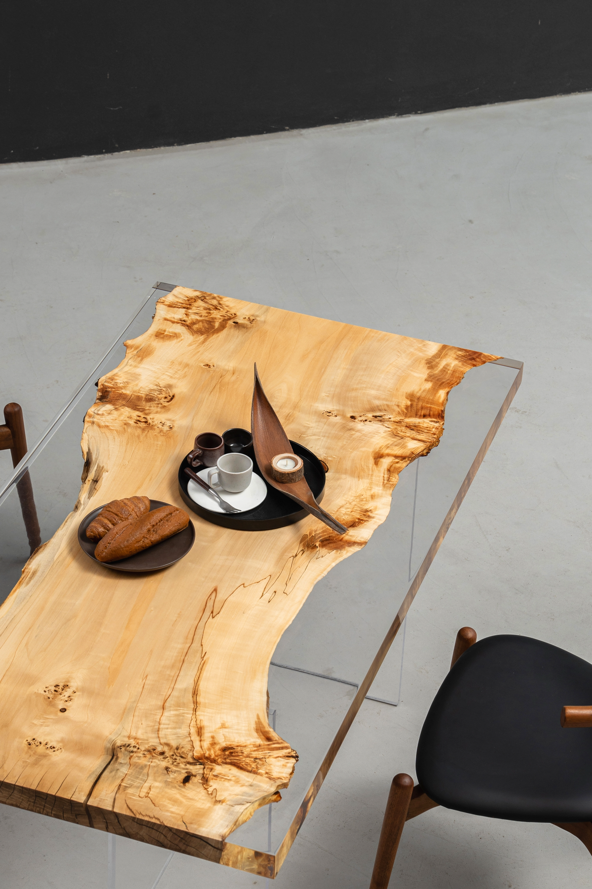 Angled overhead shot of the Clarity Prism Table with chairs, showcasing the clear epoxy-encased wood slab.
