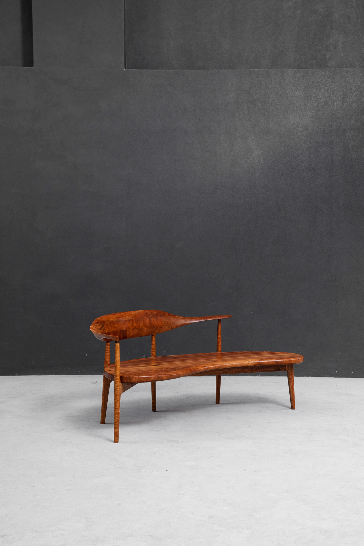 Flowing Indian rosewood Confluence Chair as a statement piece in a minimalist interior setting.