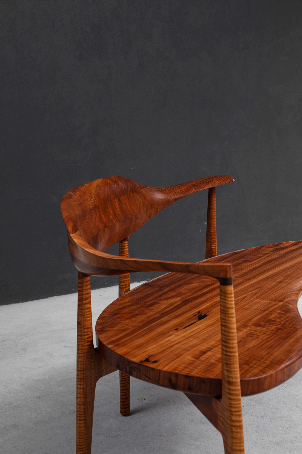Detailed angle of seat-to-frame connection showcasing rosewood joinery and ergonomic curves.