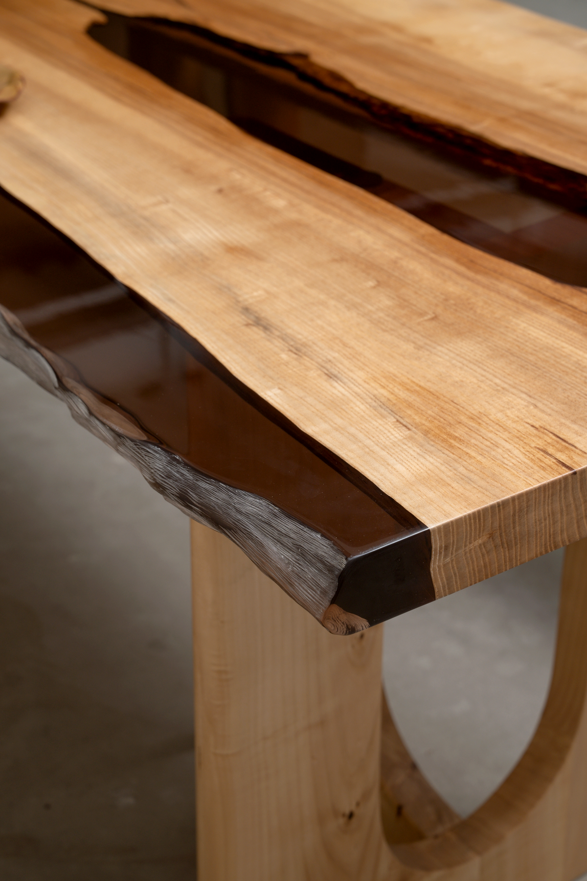 Close-up of epoxy resin edge meeting wood grain on the Convergence Table.