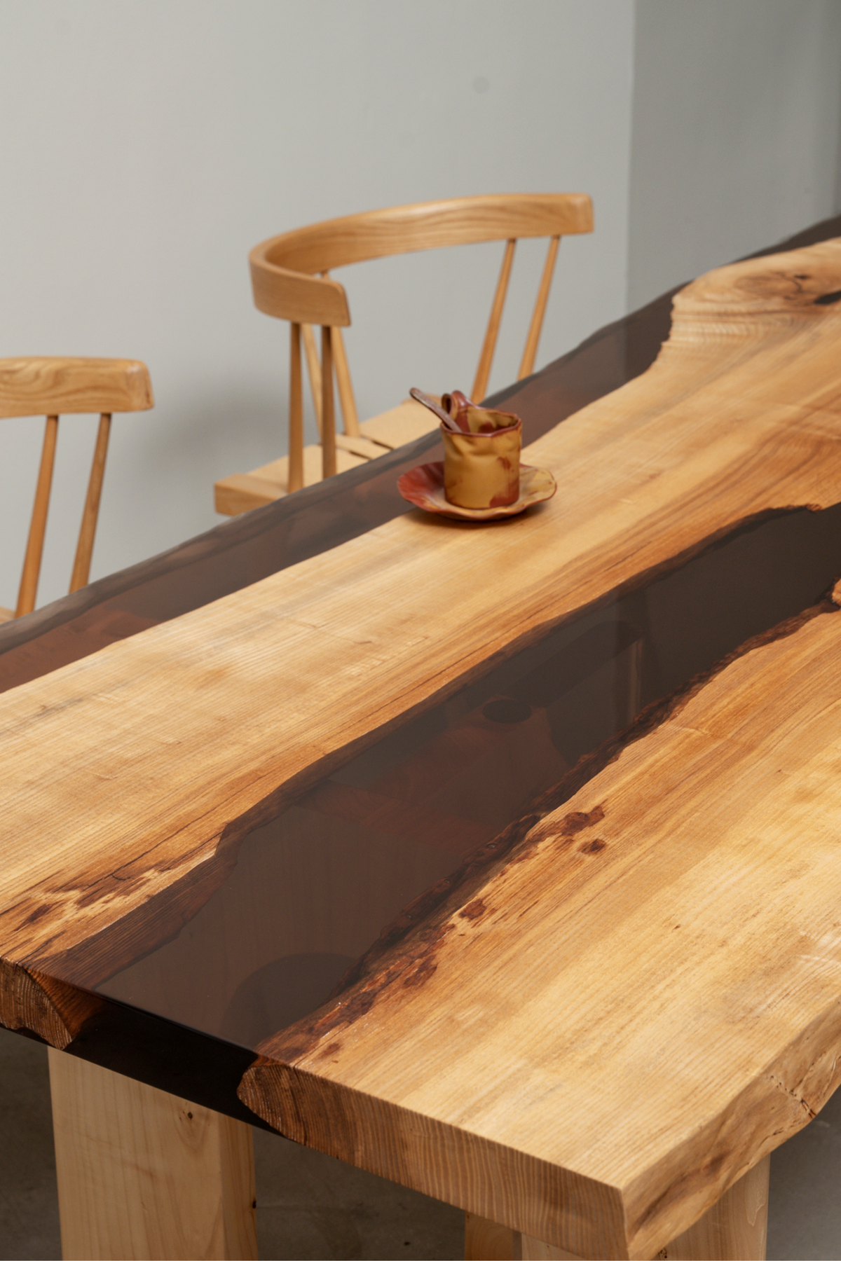 Woodslabs Convergence Table with dark epoxy resin finish and chairs in a modern dining room setting.