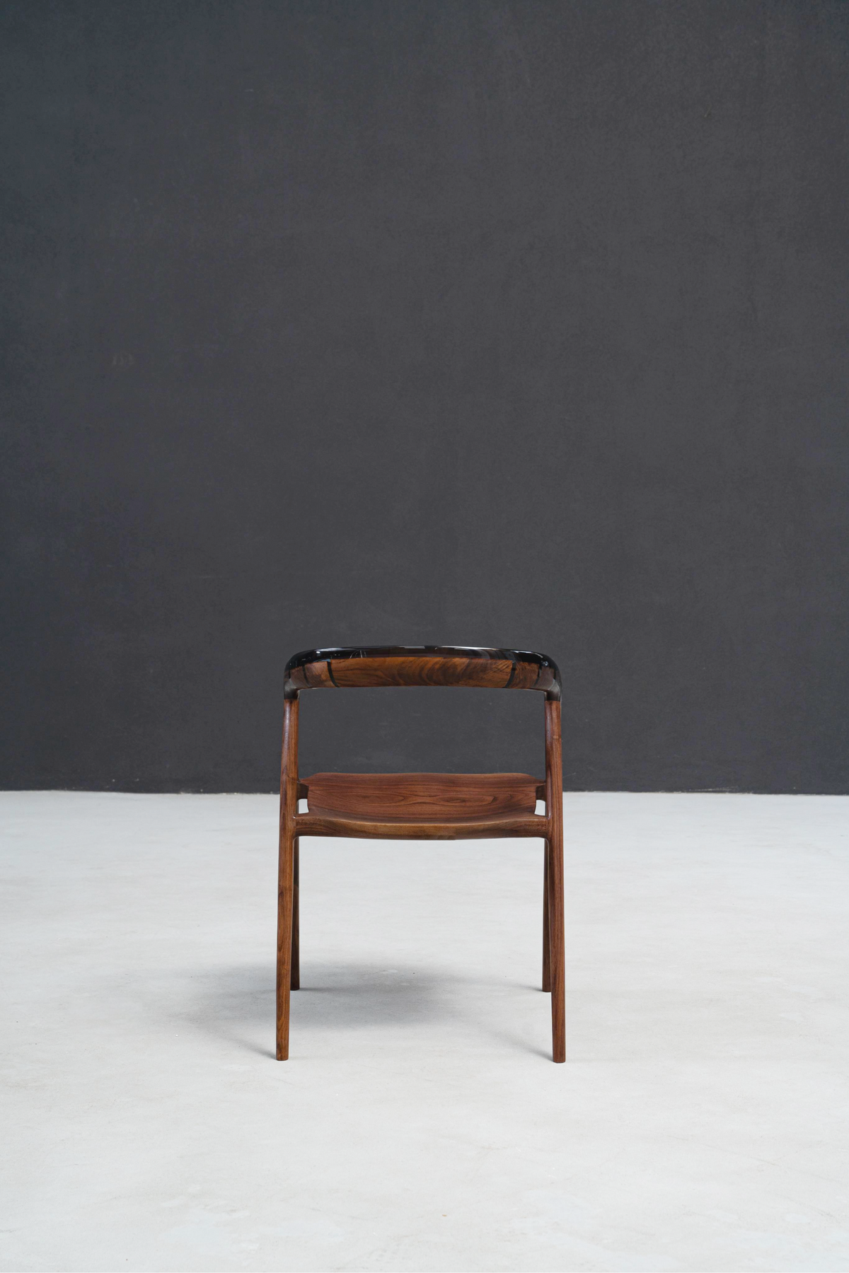 Rear view highlighting walnut grain seat and epoxy edge work across chair's backrest.