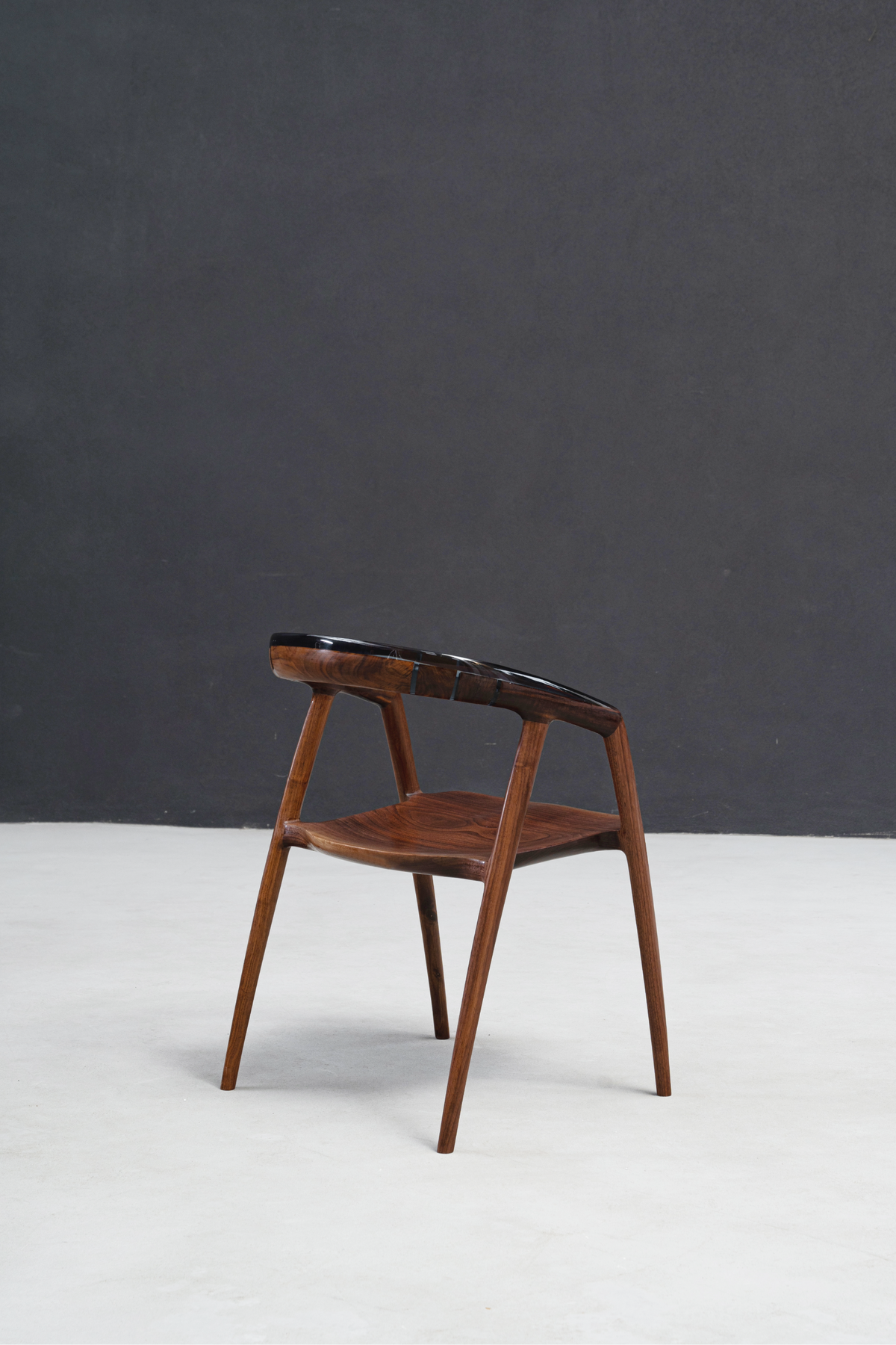 Angled profile shot of the Event Horizon Chair showcasing black walnut grain and crystalline epoxy details.