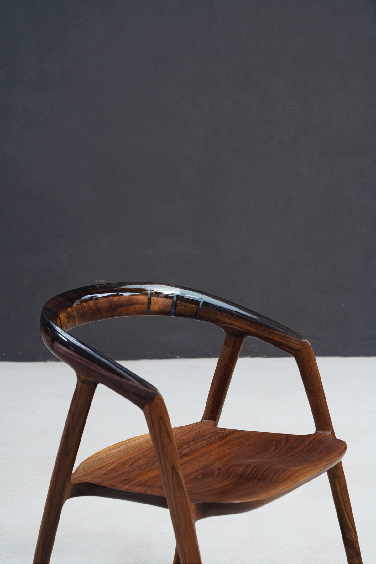 Close-up perspective of epoxy backrest seamlessly meeting black walnut frame on Event Horizon Chair.