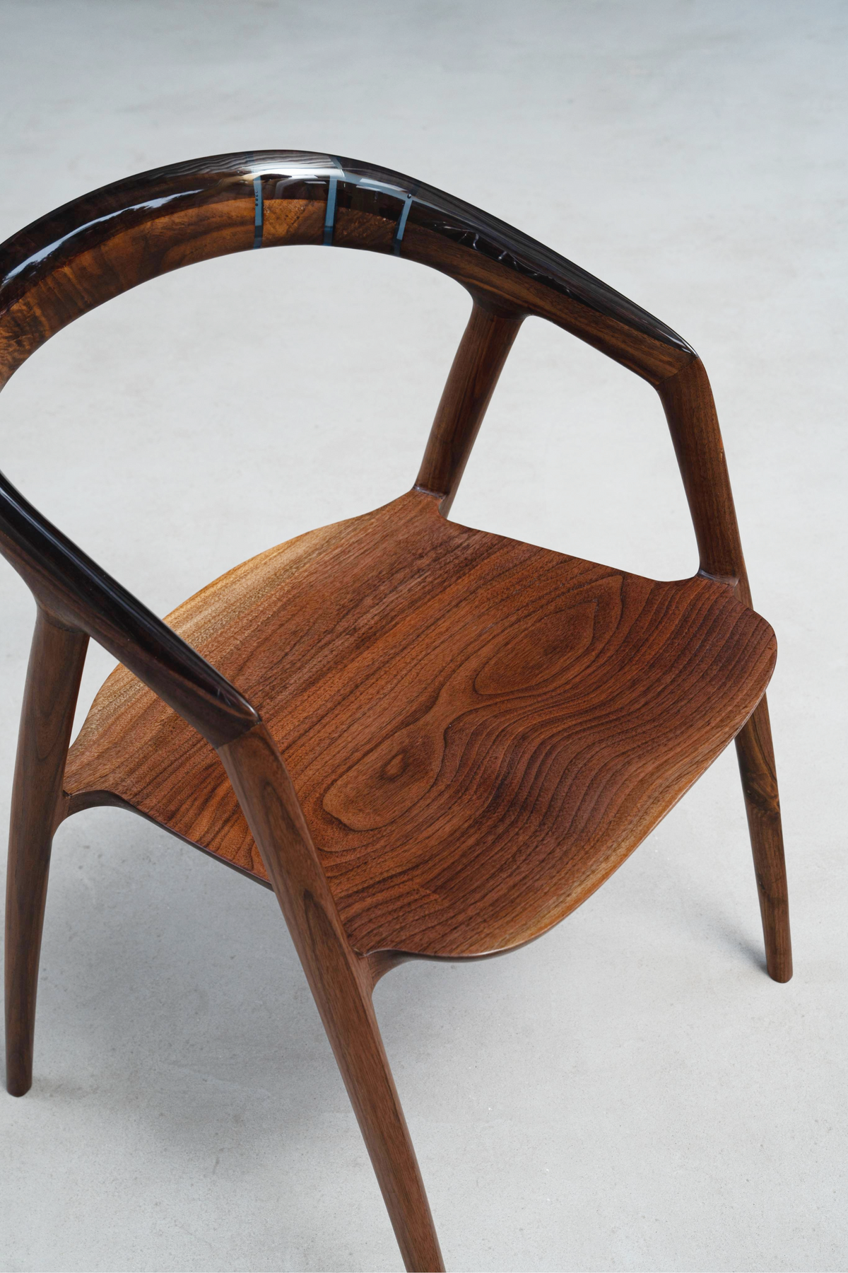 Angled downward shot of Event Horizon Chair's walnut seat and backrest craftsmanship.