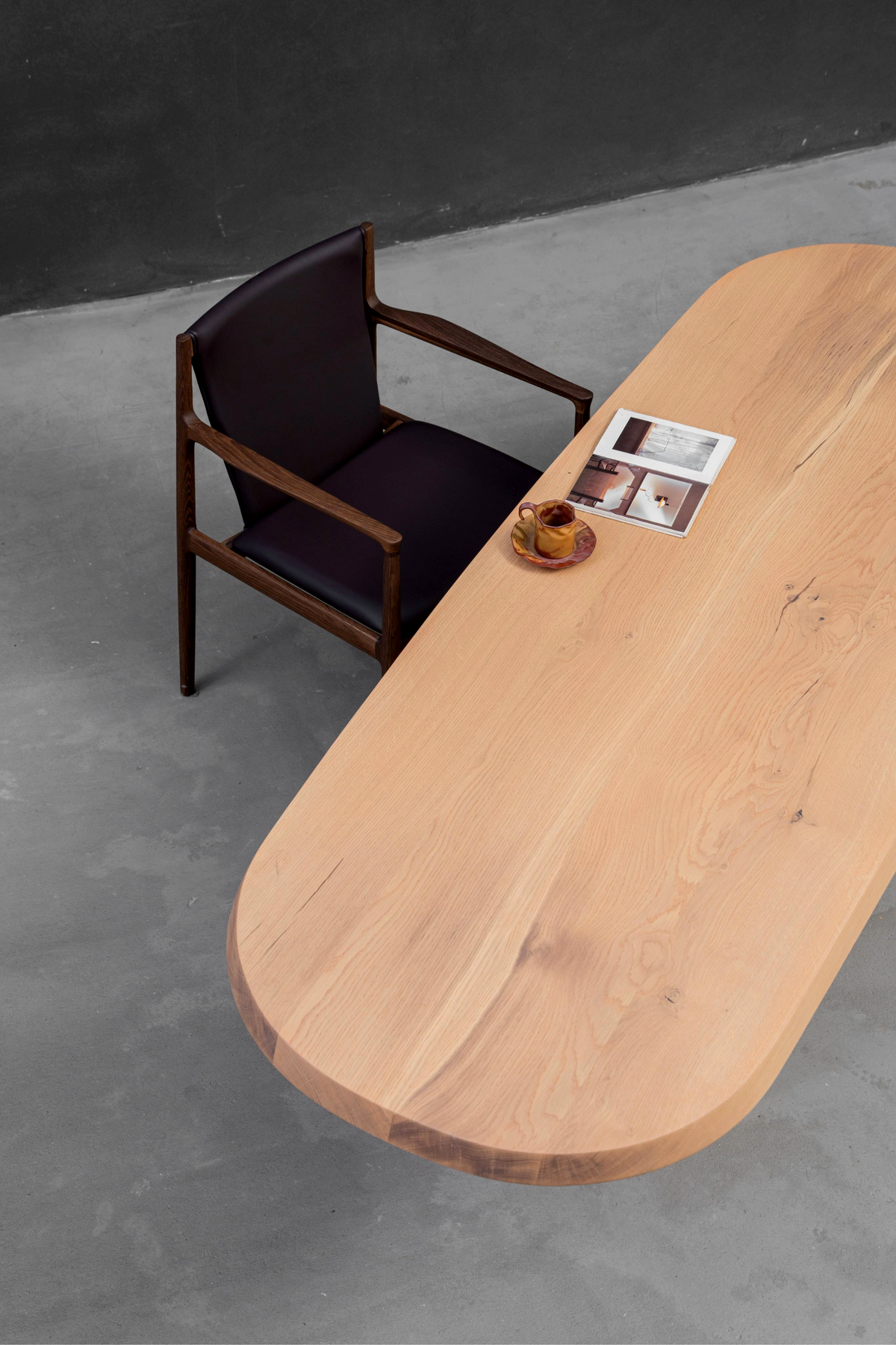 Dynamic three-quarter view of Fusion Table featuring its continuous stadium profile and ash wood tones.
