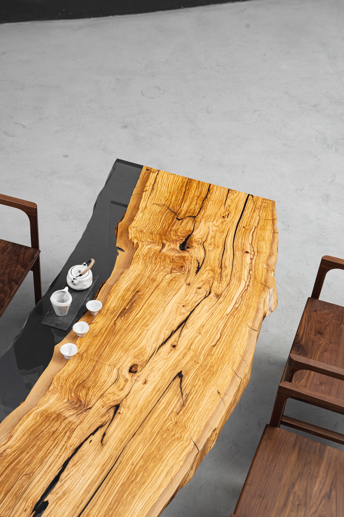 Angled aerial view of Minerva Table set with chairs, highlighting olive wood surface in context.