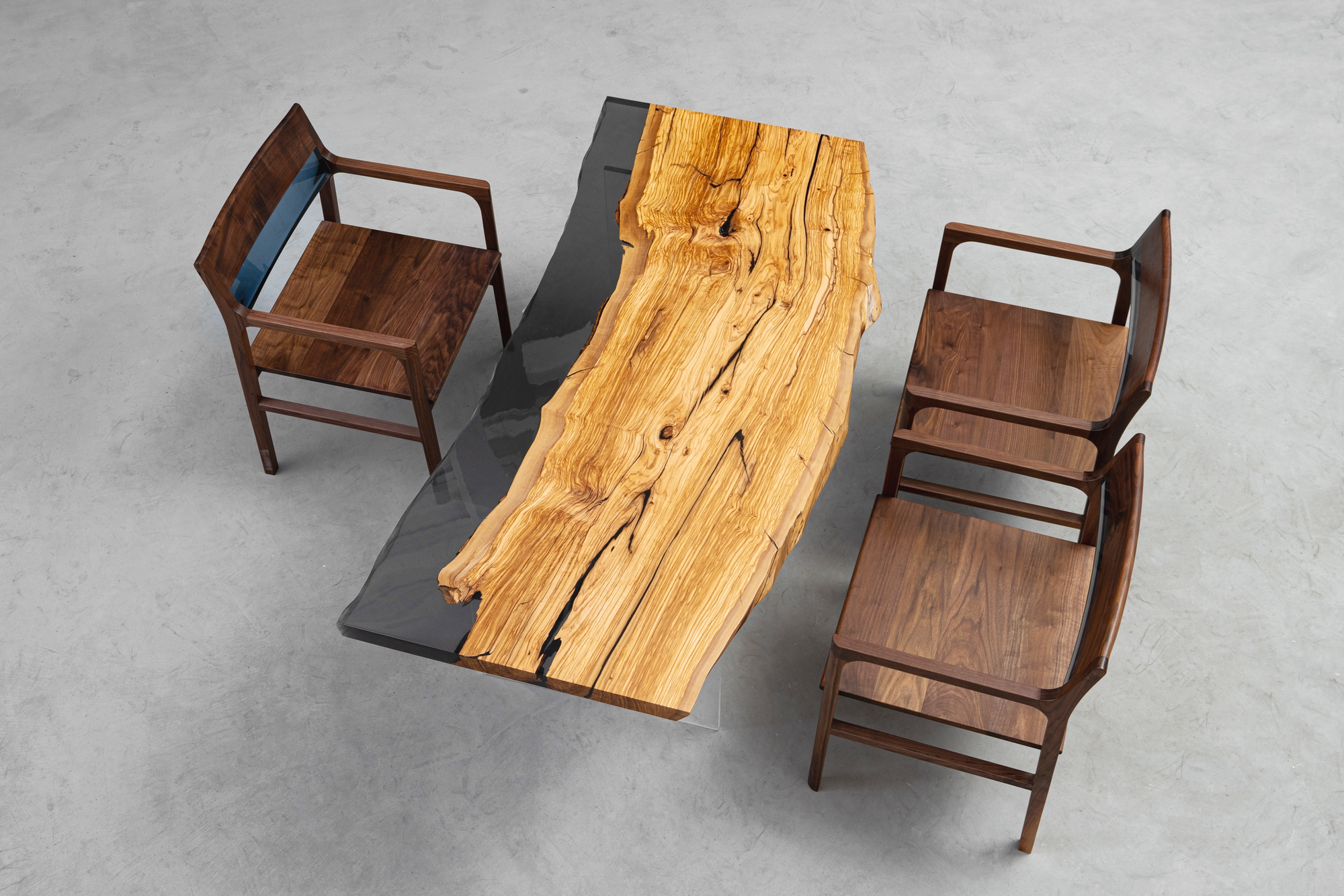 The Minerva Table with chairs against a minimalist background, showcasing Italian olive wood and epoxy resin.