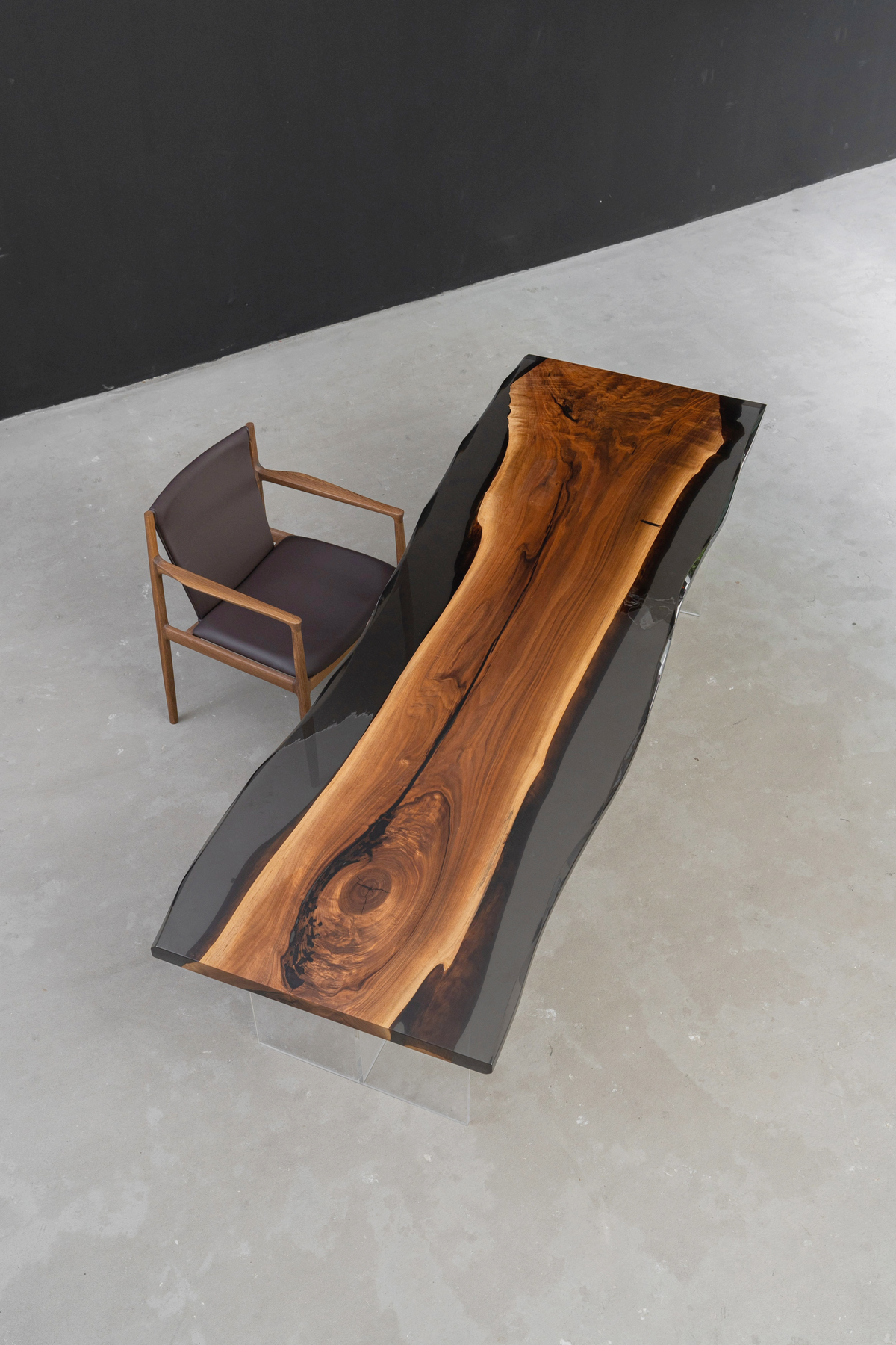 Detailed overhead angle view, the Paradox Table's epoxy edge, shown with an office chair in a minimalist workspace setting.