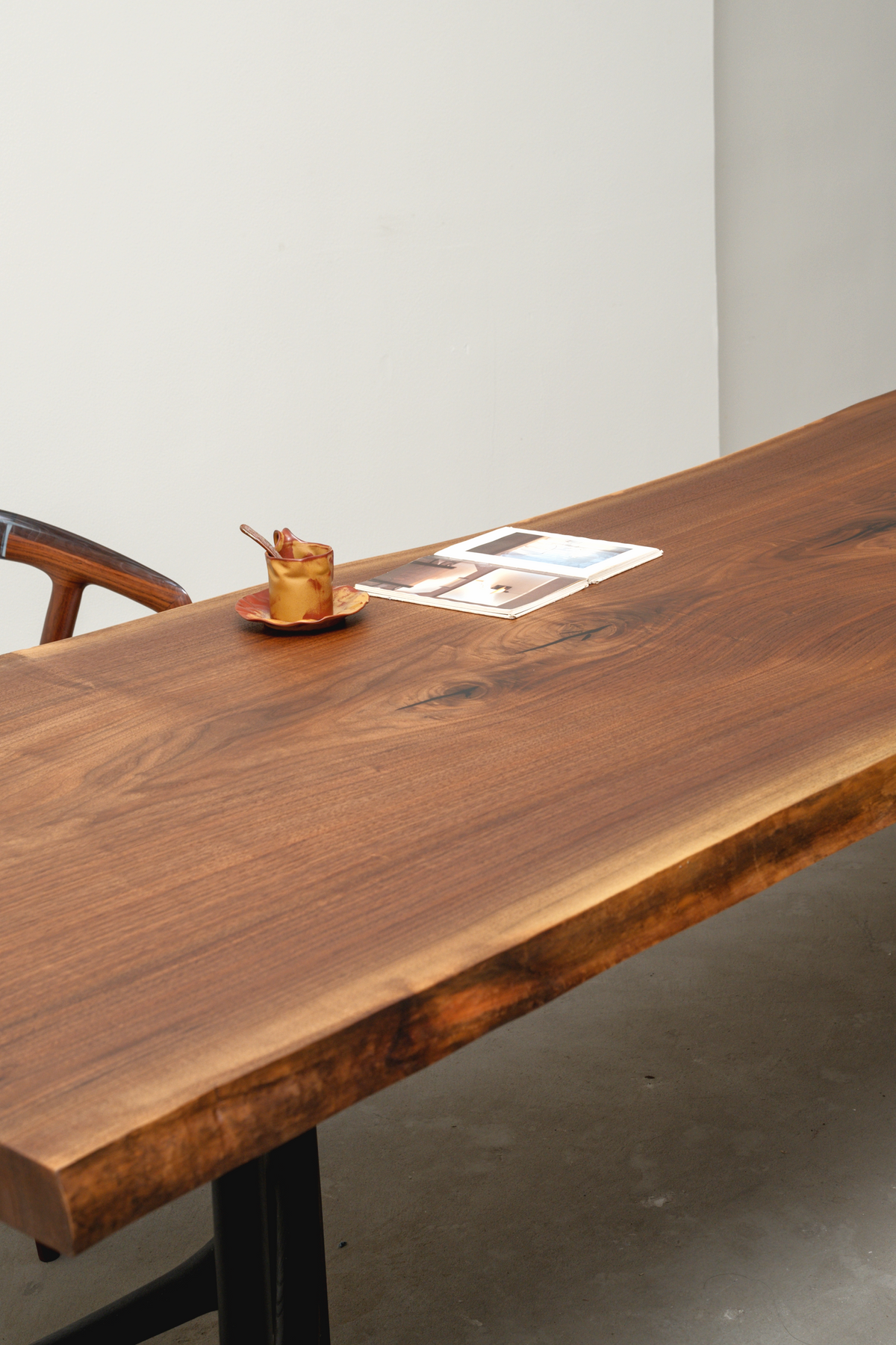 Side angle view of the Span of Influence Table, displaying the craftsmanship of its solid wood slab and base joinery