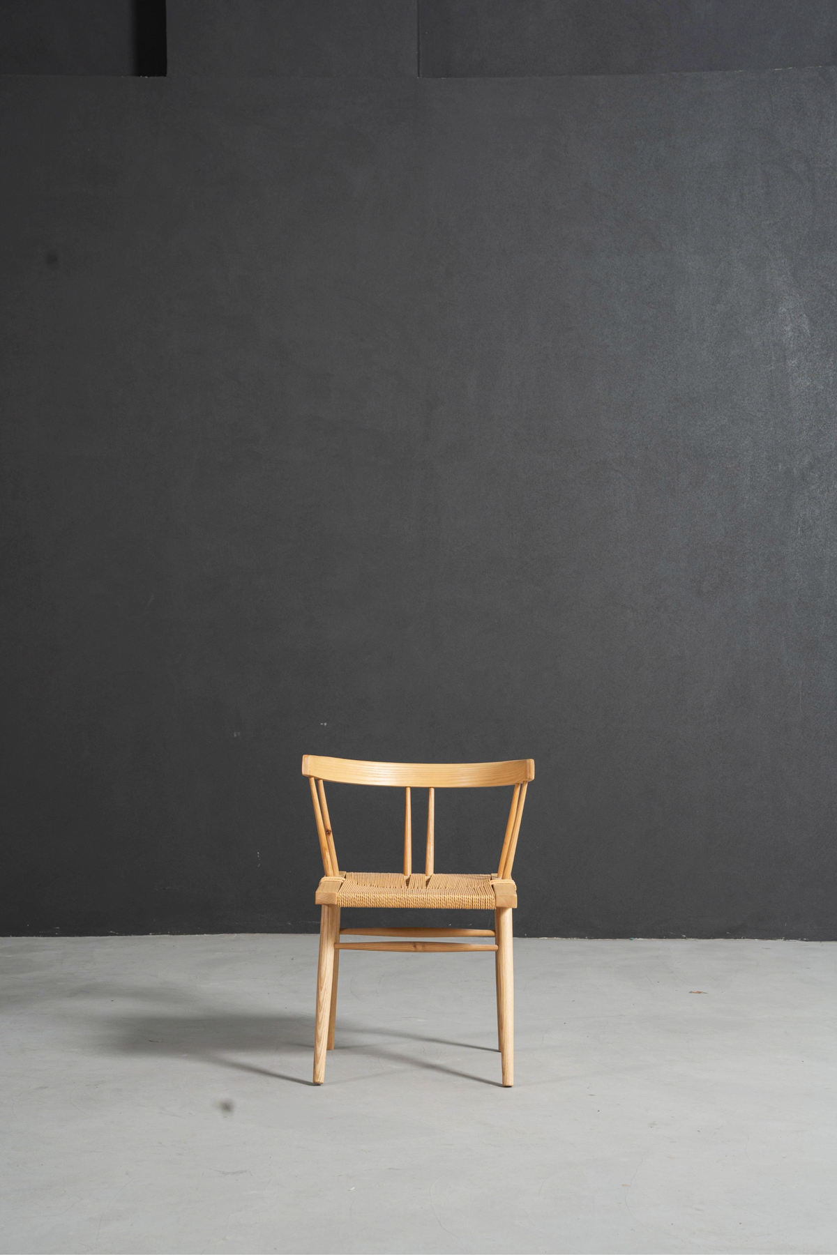 Front perspective of the Symphony Chair showcasing its clean lines and Nakashima-inspired form in a minimalist setting.