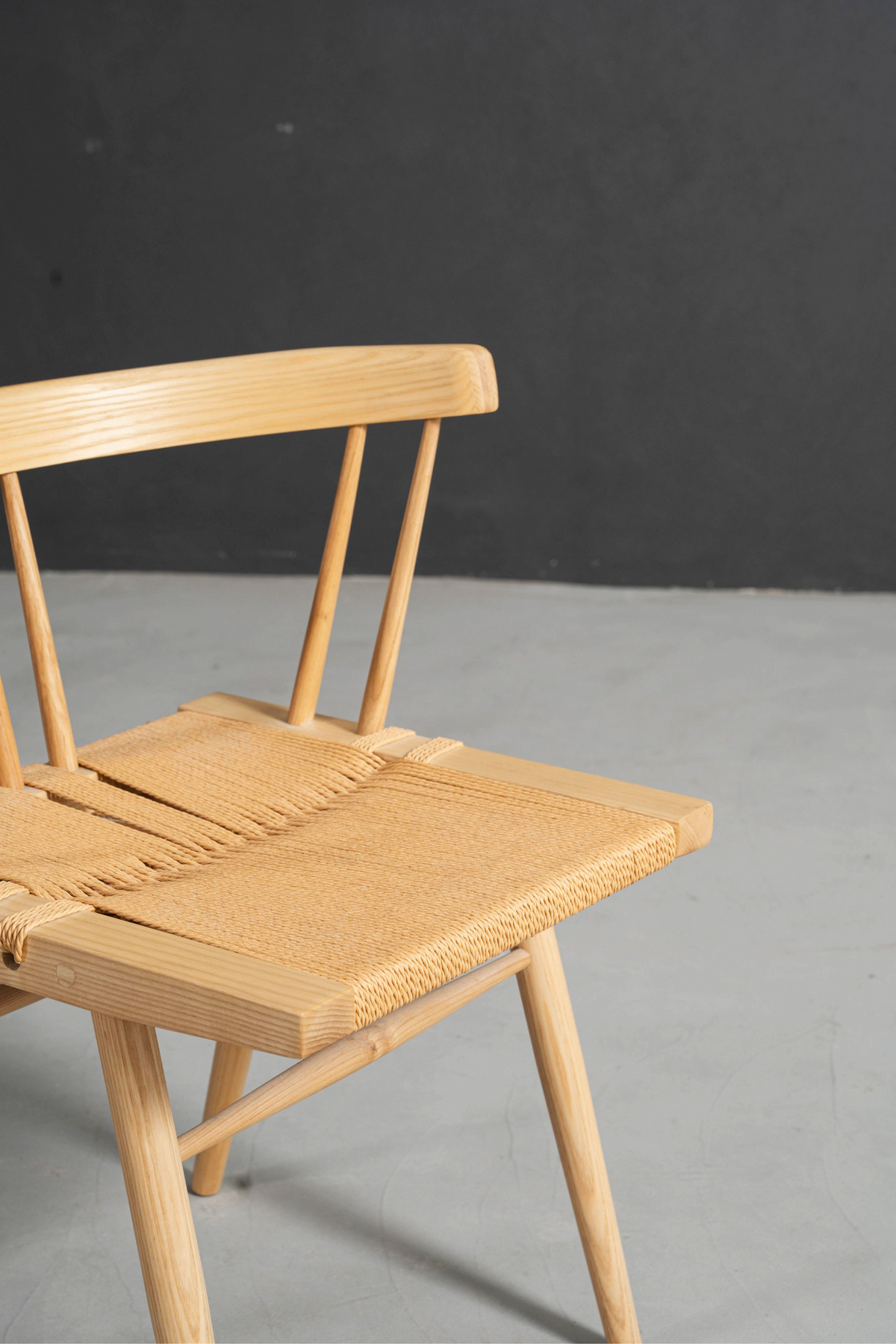 Angled front detail of seat in clean minimalist setting, highlighting form and materials.
