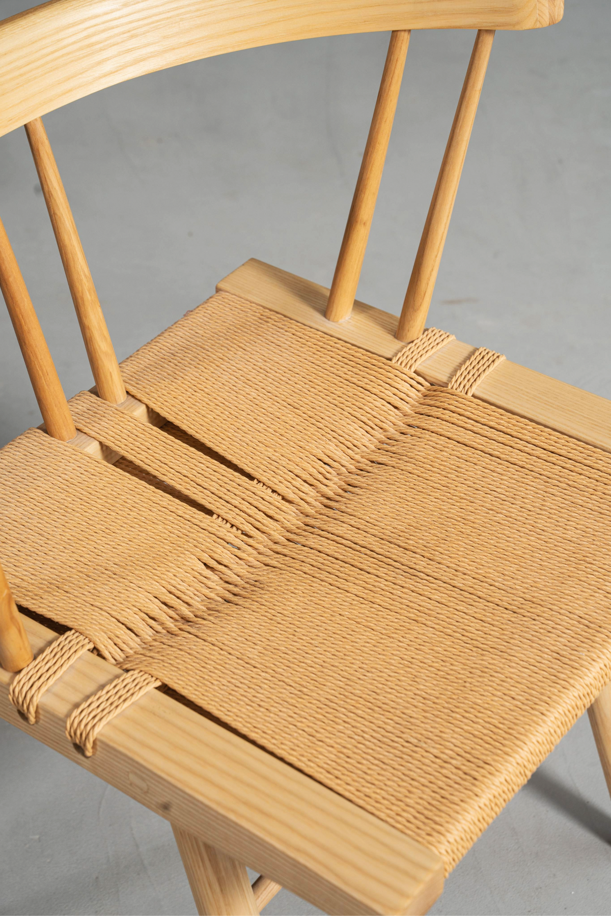 Nakashima-inspired Symphony Chair featuring ash wood frame and woven jute seat.