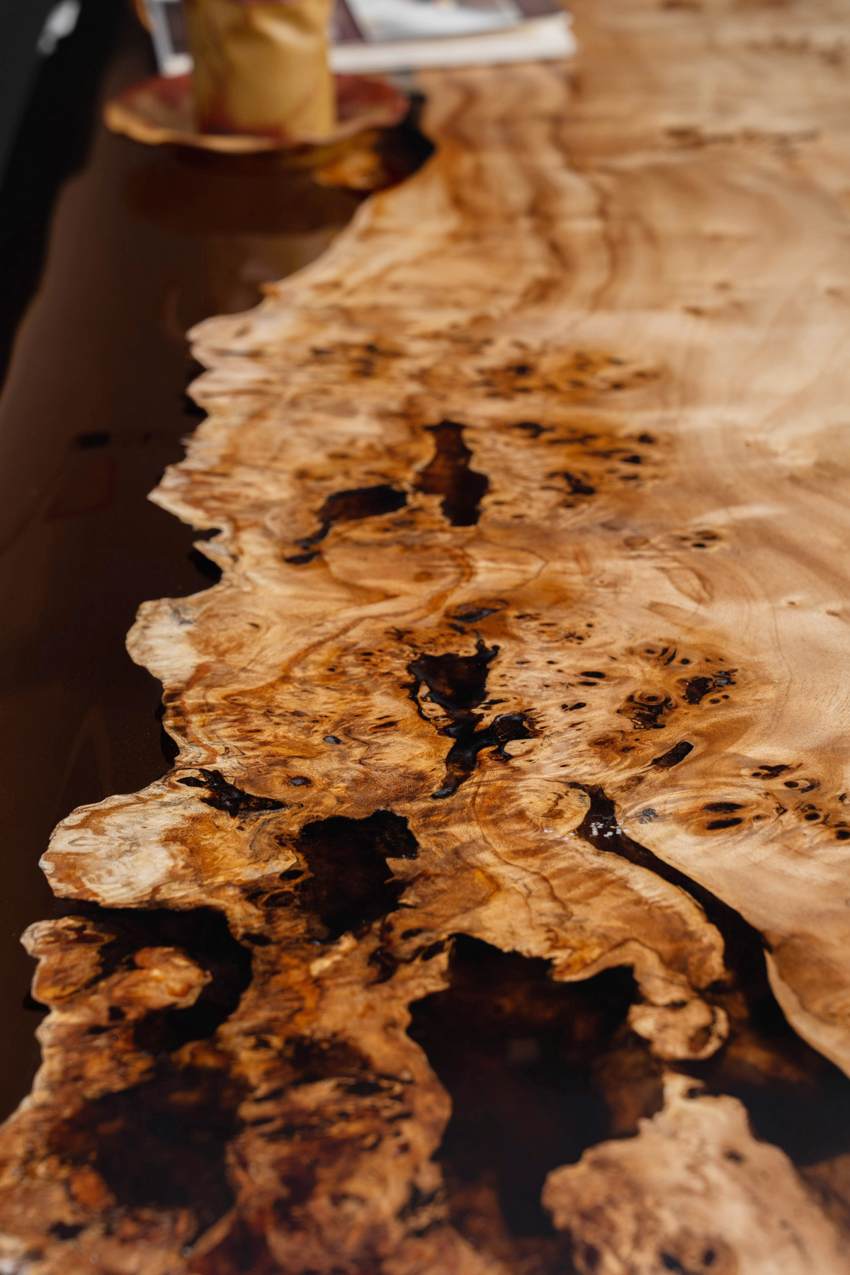 Macro shot of the Synthesis Table's edge detail showing organic Mappa Burl flowing into polished epoxy.