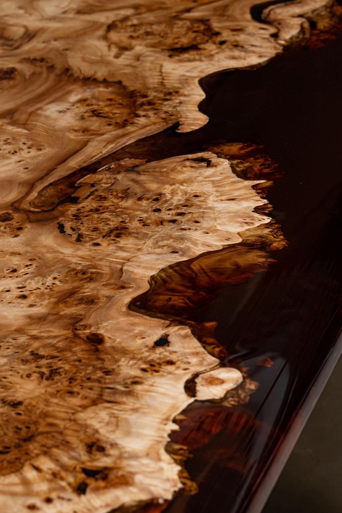 Close-up where live edge wood meets smooth, curved epoxy resin in handcrafted detail.