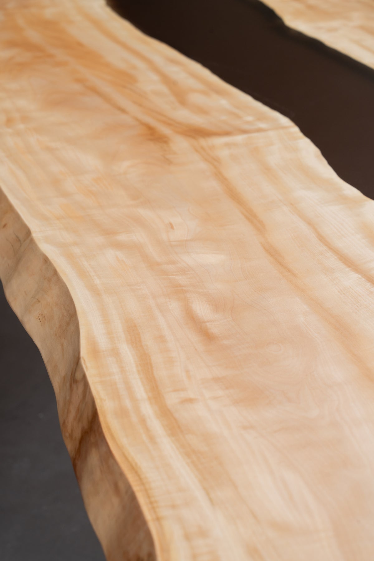 Edge close-up of Japanese horse chestnut grain on Tochi Horizon table revealing live edge waveform.