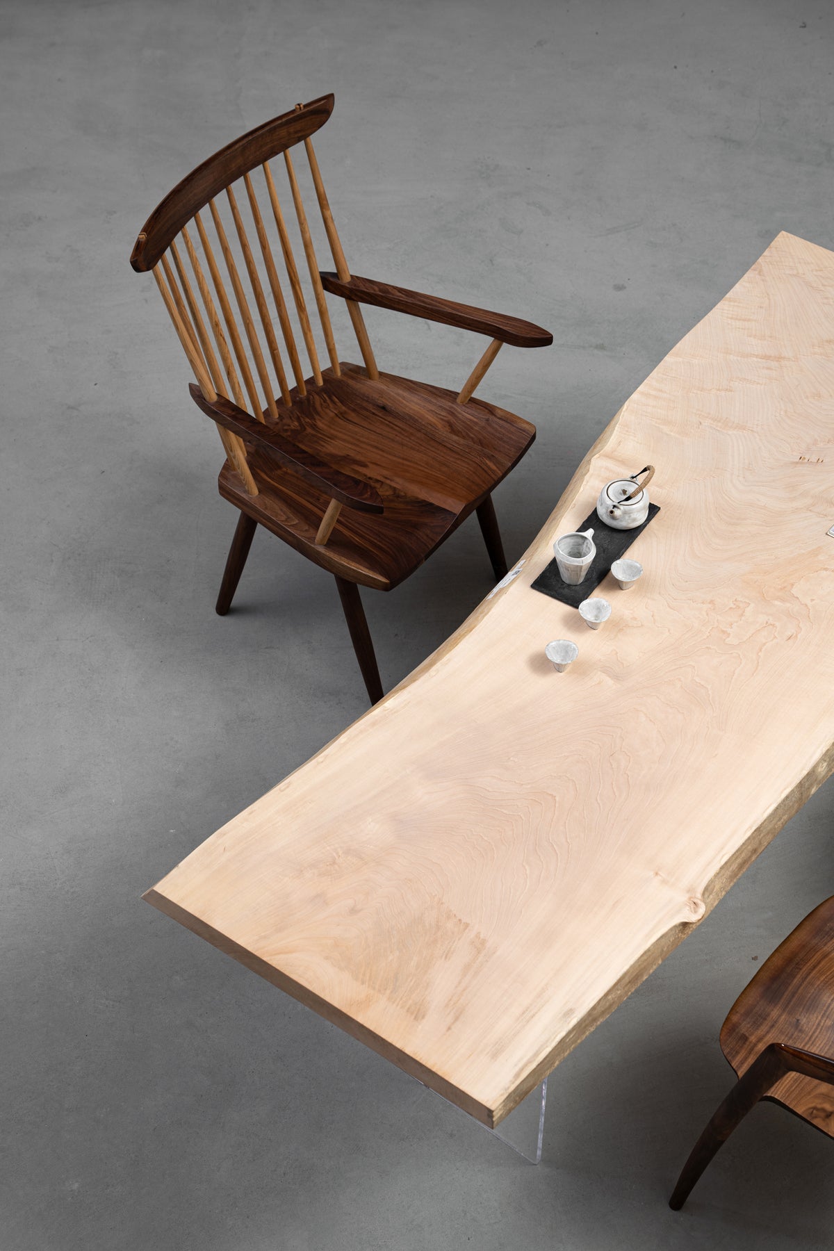 Angled portrait view of Tochi Veil solid wood slab showing the light brushed surface and organic undulating edges