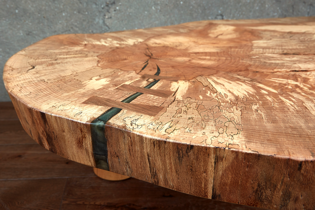 Close-up of a green epoxy resin accent and traditional dovetail key set into the stunning spalted beech grain of the Cocoon Table.