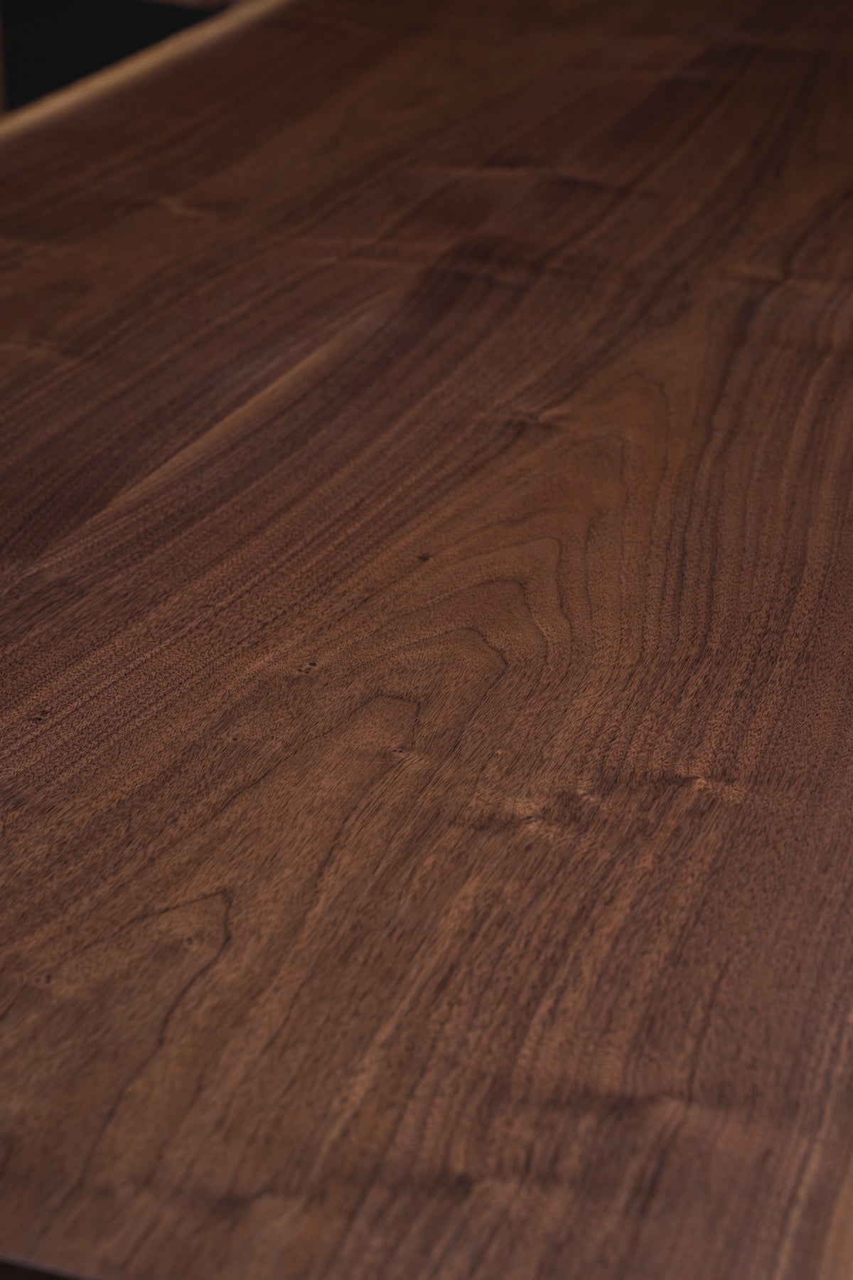 Close-up detail of the table grain, the Duskwood Frontier dining table, revealing natural walnut contours and hand-finished texture.