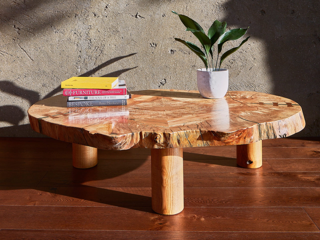 Luxury Cocoon Lounge Table in spalted beech wood with cylindrical legs in a modern, sunlit interior setting.