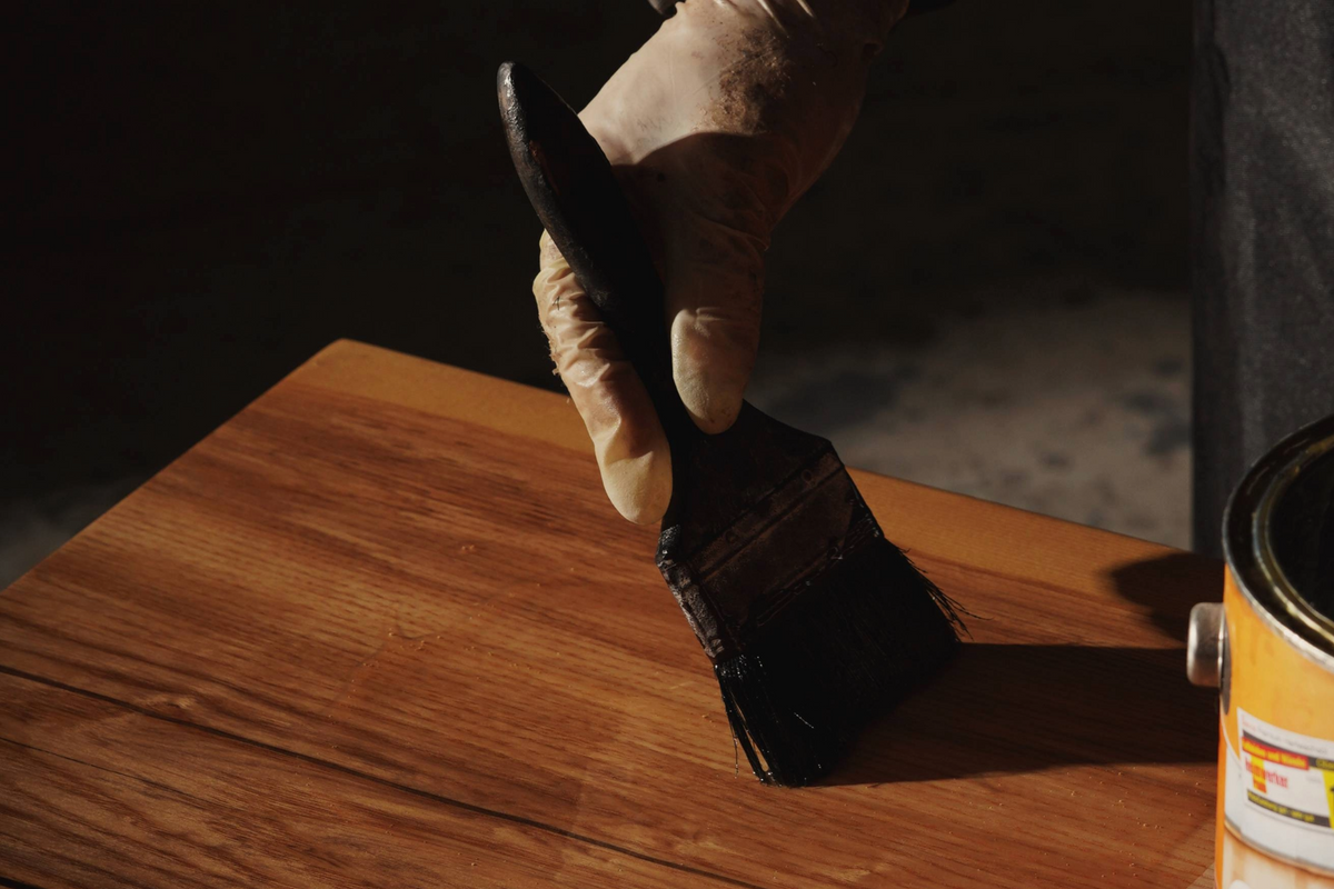 Woodslabs artisan applying a varnish to a live-edge wood slab, highlighting the deep wood grain.